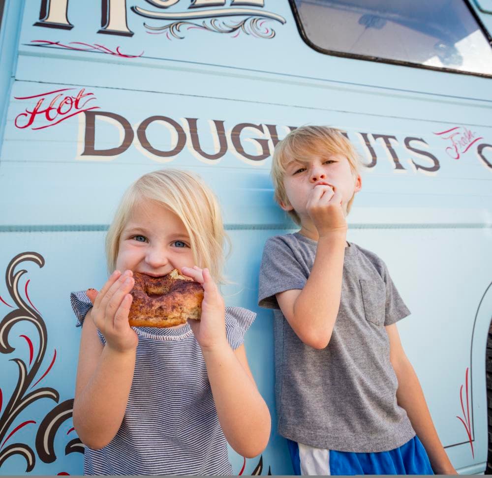 Little girl eating doughnut outside of Hole Doughnut Little girl eating doughnut outside of Hole Doughnut