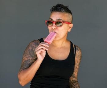 Woman wearing sunglasses eating a popsicle Woman wearing sunglasses eating a popsicle