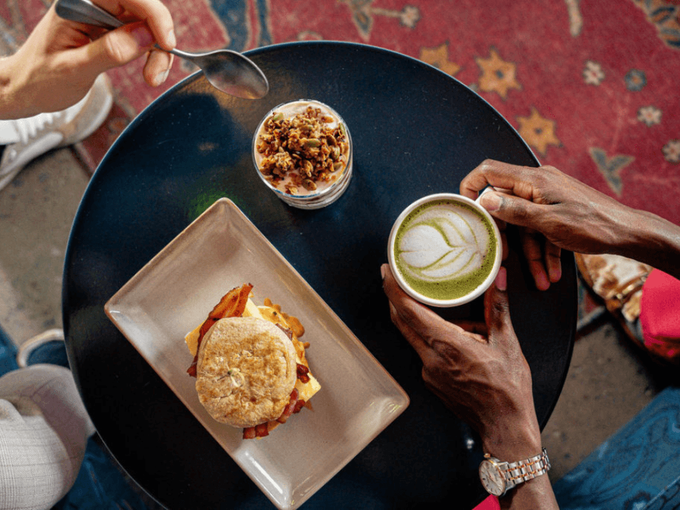 two people eating granola yogurt and breakfast sandwich with a matcha latte two people eating granola yogurt and breakfast sandwich with a matcha latte