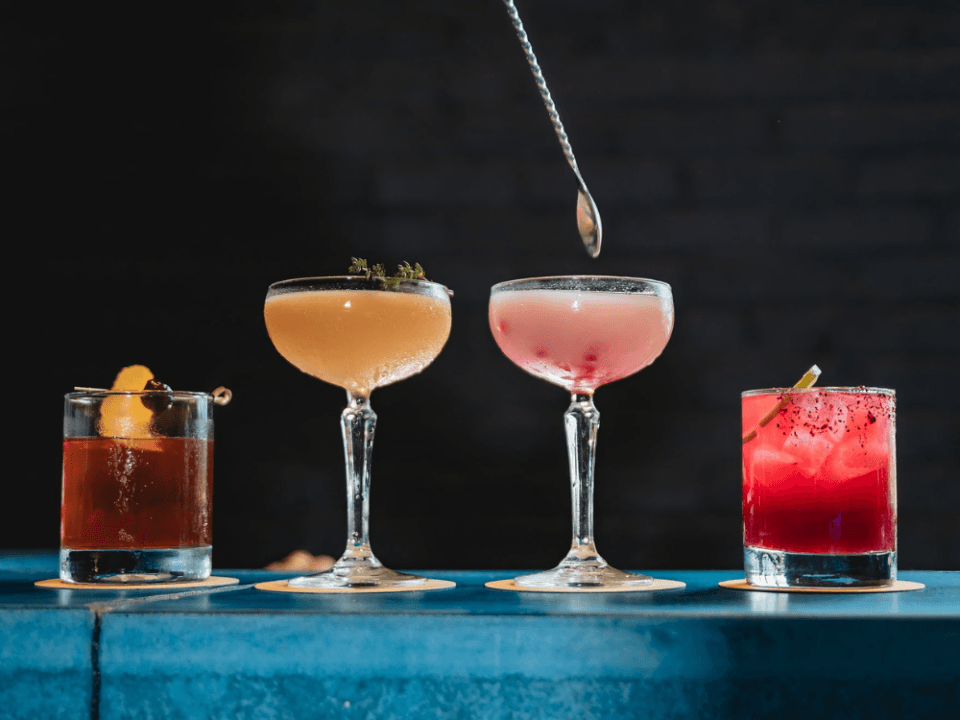 four drinks on a blue bar, two in low ball glasses and two in coop glasses four drinks on a blue bar, two in low ball glasses and two in coop glasses