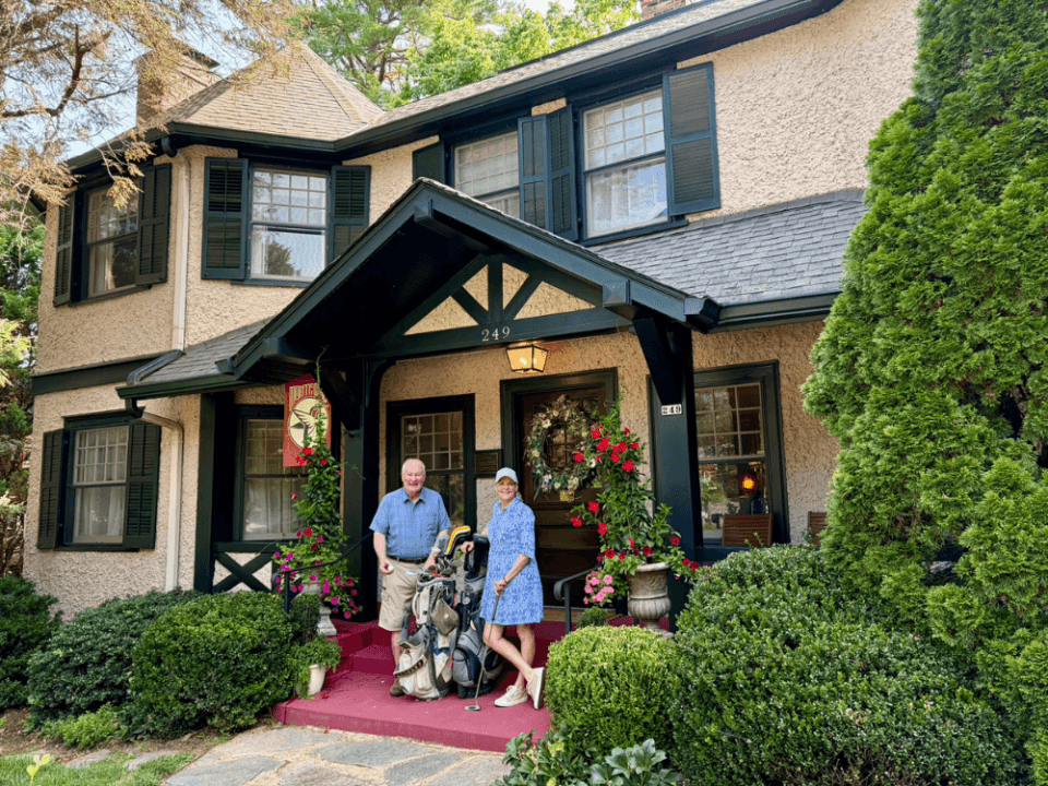 Innkeepers Dan and Diane stand with golf clubs on the front porch of Pinecrest Bed & Breakfast, a historic home in Asheville NC Innkeepers Dan and Diane stand with golf clubs on the front porch of Pinecrest Bed & Breakfast, a historic home in Asheville NC