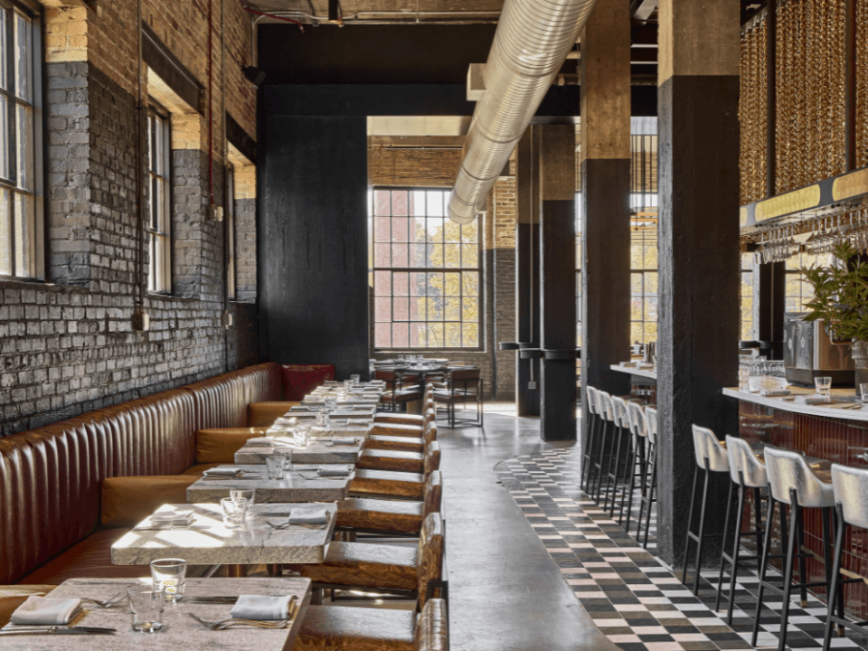 a restaurant with tables in a line on one side and bar seating on the other with a painted brick interior and checkered floor a restaurant with tables in a line on one side and bar seating on the other with a painted brick interior and checkered floor