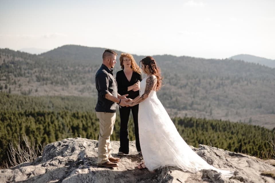 Bride and Groom hold hands as Michelle officiates their wedding ceremony overlooking a mountain vista. Bride and Groom hold hands as Michelle officiates their wedding ceremony overlooking a mountain vista.
