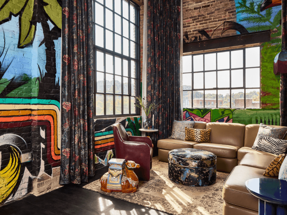 living room with graffiti art on the wall, a tan leather couch, and unique ottoman and camel end table living room with graffiti art on the wall, a tan leather couch, and unique ottoman and camel end table