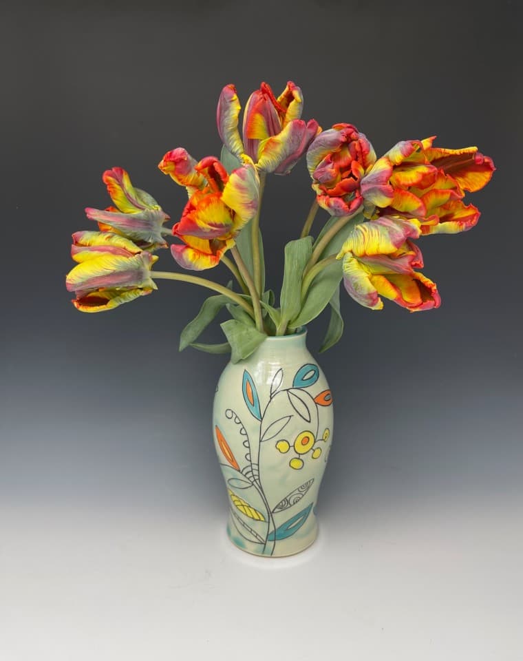Handmade vase in Aqua glaze. With Vine pattern with turquoise, yellow and orange details. Tulips from Blazing Star Flower Farm in Alexander, NC. Handmade vase in Aqua glaze. With Vine pattern with turquoise, yellow and orange details. Tulips from Blazing Star Flower Farm in Alexander, NC.