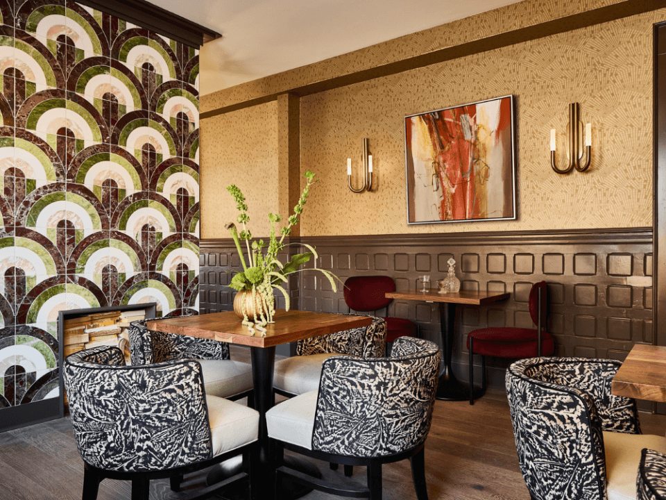 Room with beautiful tiled fireplace and three seating areas with black and white patterned chairs and wooden tables Room with beautiful tiled fireplace and three seating areas with black and white patterned chairs and wooden tables