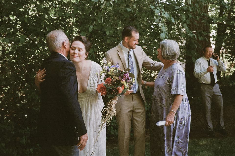 A couple embracing their parents during group family portraits A couple embracing their parents during group family portraits