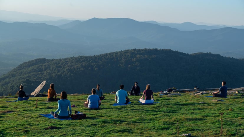 A group of people doing yoga in a mountain field along Bearwallow Trail in Asheville