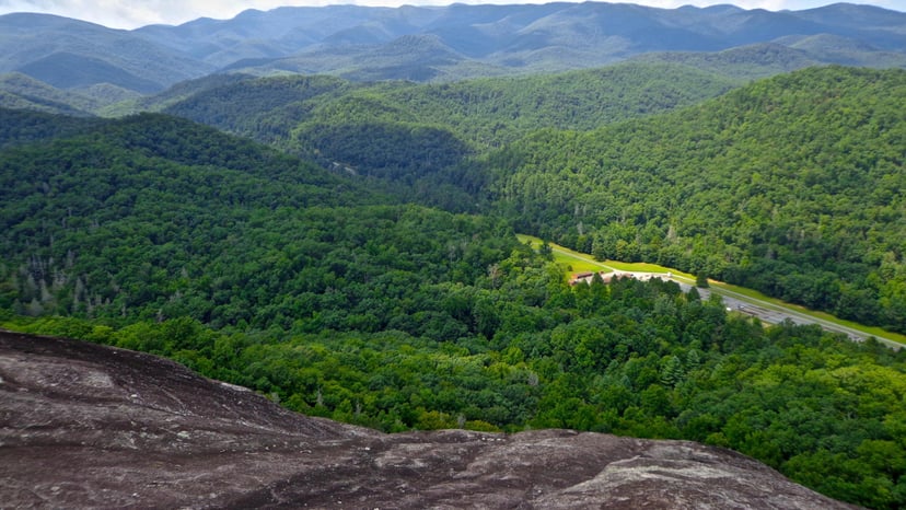 An aerial view of lush forest and rolling hills from John Rock Trail in Asheville