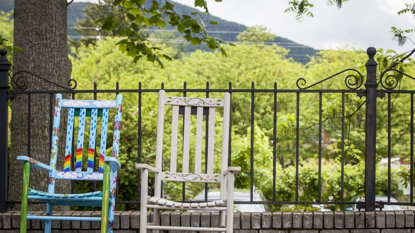 two rocking chairs are on a deck in front of a stunning green mountain view