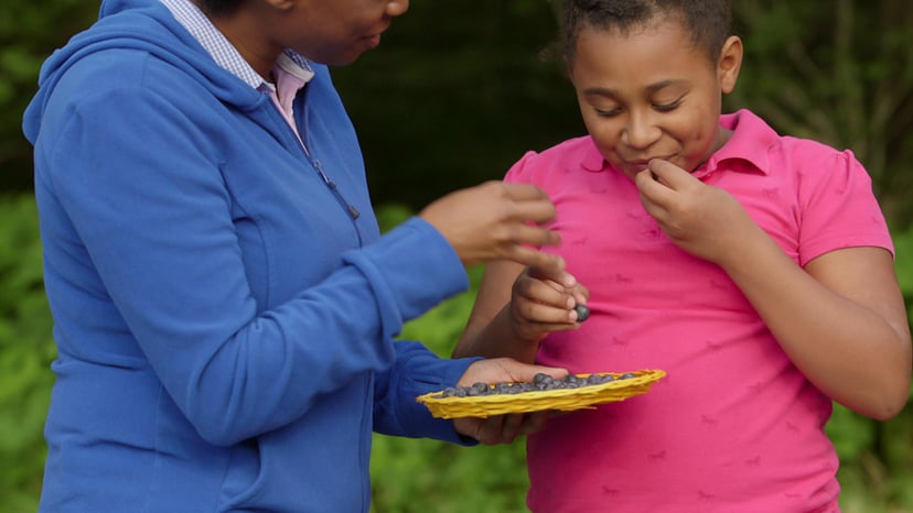 A parent and child smile as they eat fresh-picked berries in Asheville