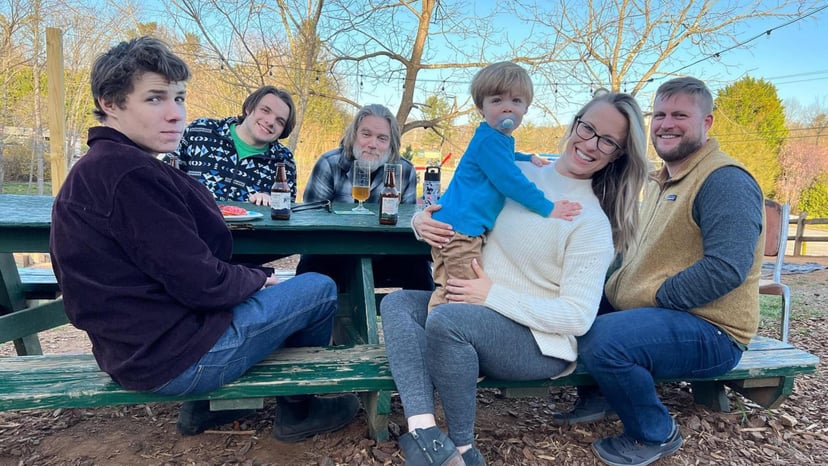 a family sits on a park bench smiling.