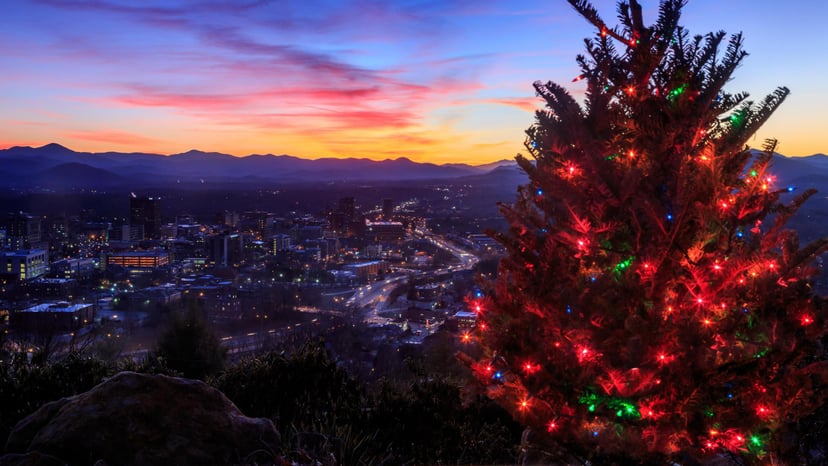 an overlook of Asheville at sunset with a christmas tree in the foreground