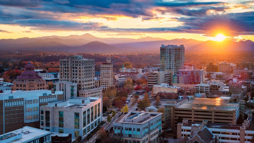 The sun rises behind downtown Asheville